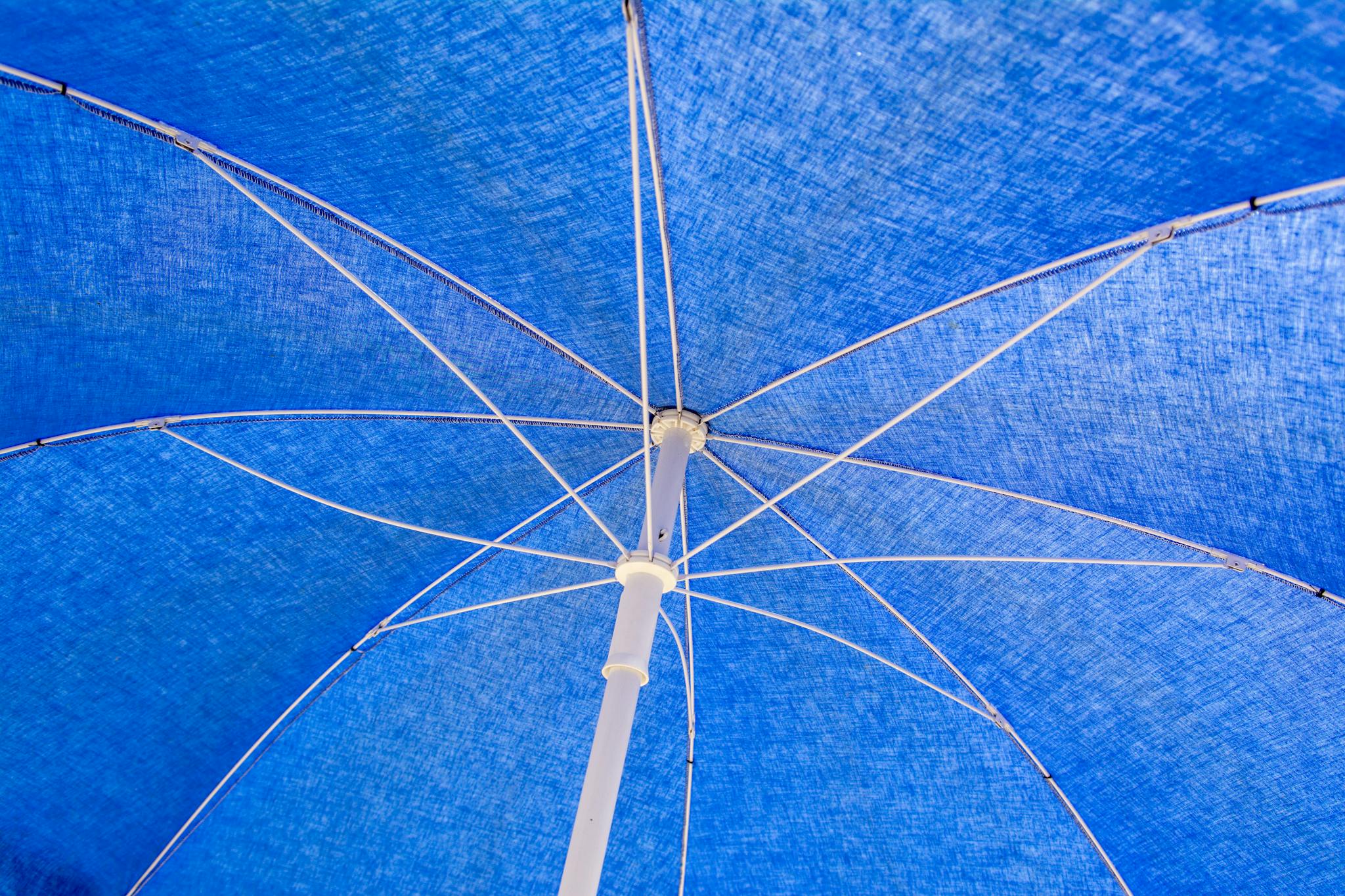 Detailed close-up of the blue fabric and framework of an open umbrella.